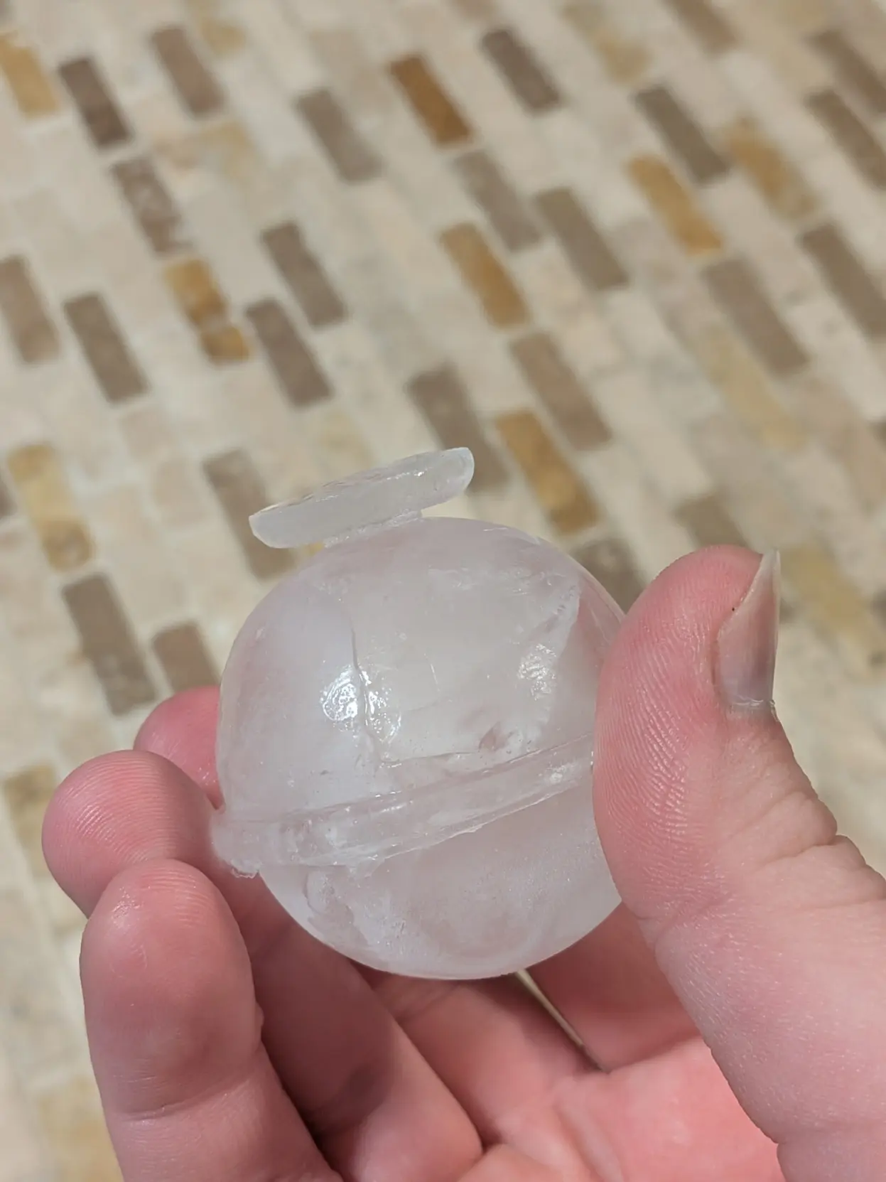 photo of me holding an ice ball between my fingers. it extrudes and fans out a bit at the top, but not past the actual diameter, like a very insufficient flared base